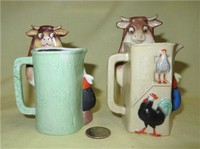 Two multicolored S&V pitchers of cow caricature being milked, front