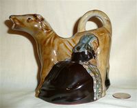 Guernsey Pottery brown cow creamer with kneeling milkmaid, left