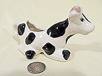 Kneeling black and white cow creamer