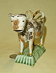 orange and brown sponged prattware cow on light green base, incised lid with hoop, front