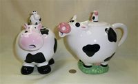 Two spherical cow teapots with calves on lids
